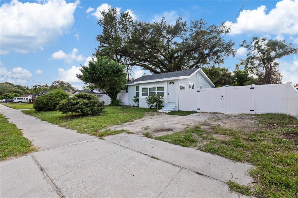A light blue house with a white fence and a large tree in the front yard — 8714 N BLVD, TAMPA, FL