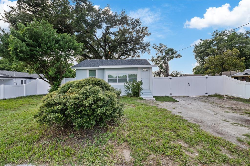 A small, light blue house with a white fence and a large bush in the yard — 8714 N BLVD, TAMPA, FL