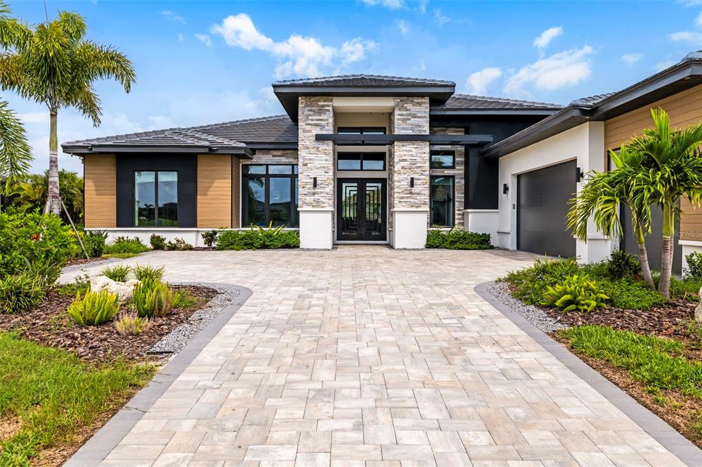 A modern single-story house with a stone facade, dark trim, and a paved driveway — 4116 BUTTE TRAIL, BRADENTON, FL
