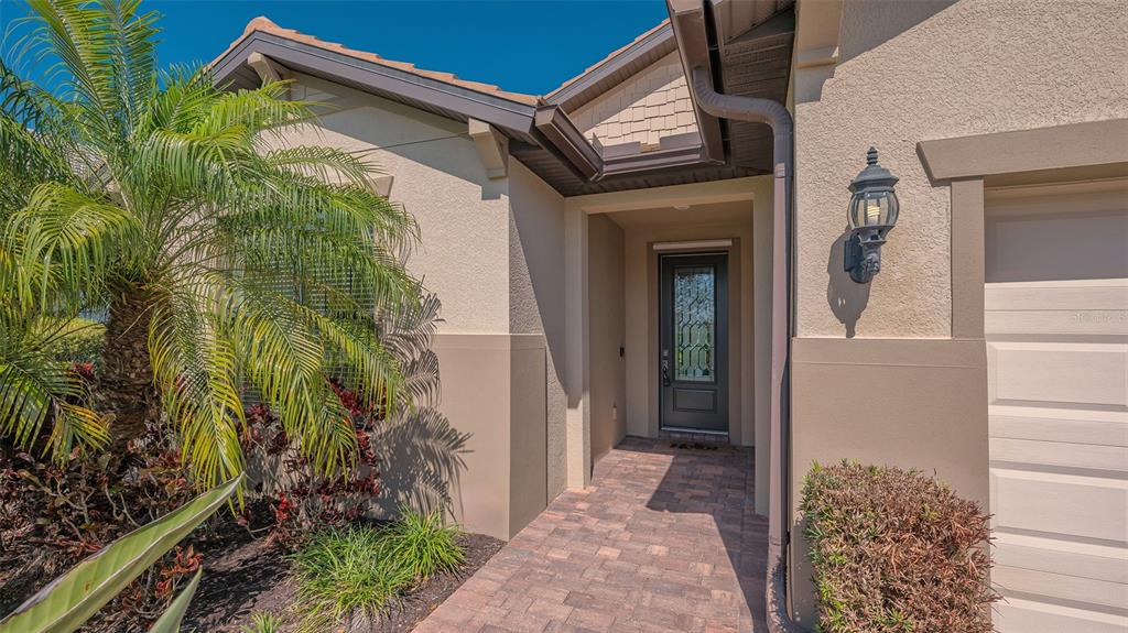 The exterior of a home features a paved walkway leading to a dark front door — 5824 WILLOW MARSH COURT, SARASOTA, FL