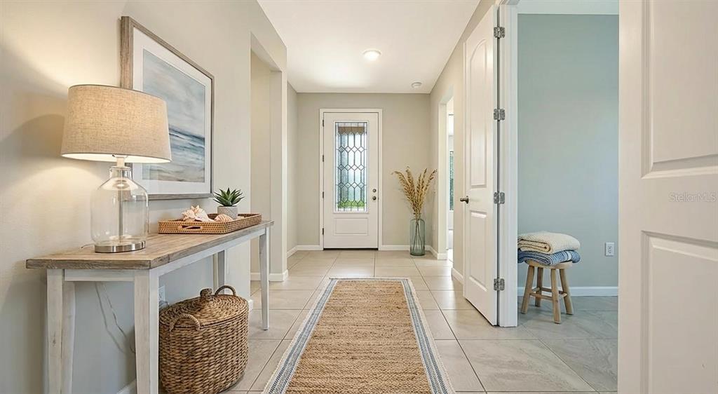 A bright entryway features a console table, a woven rug, and a white front door — 5824 WILLOW MARSH COURT, SARASOTA, FL