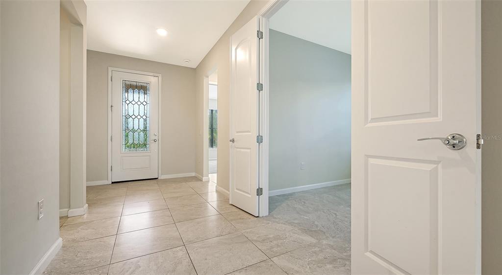 An entryway with light tile flooring leads to a white front door and interior rooms — 5824 WILLOW MARSH COURT, SARASOTA, FL