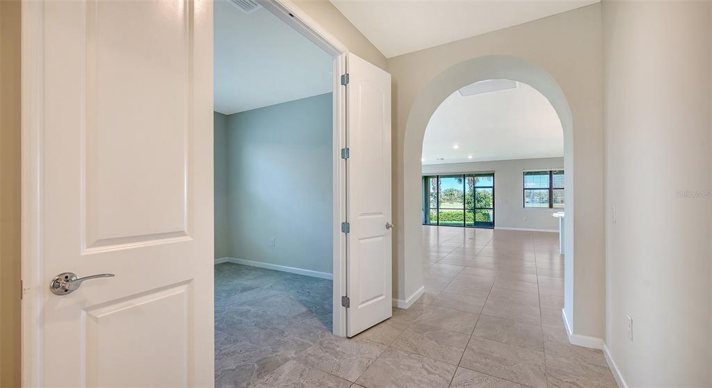 A view from a hallway into a room with tile floors and an arched entryway — 5824 WILLOW MARSH COURT, SARASOTA, FL