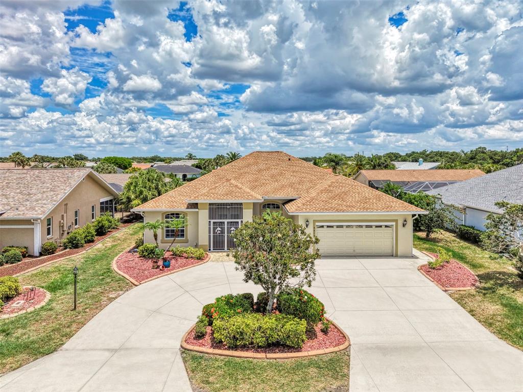A single-story suburban house features a tan exterior, a two-car garage, and a circular driveway — 5879 MADISON ROAD, VENICE, FL