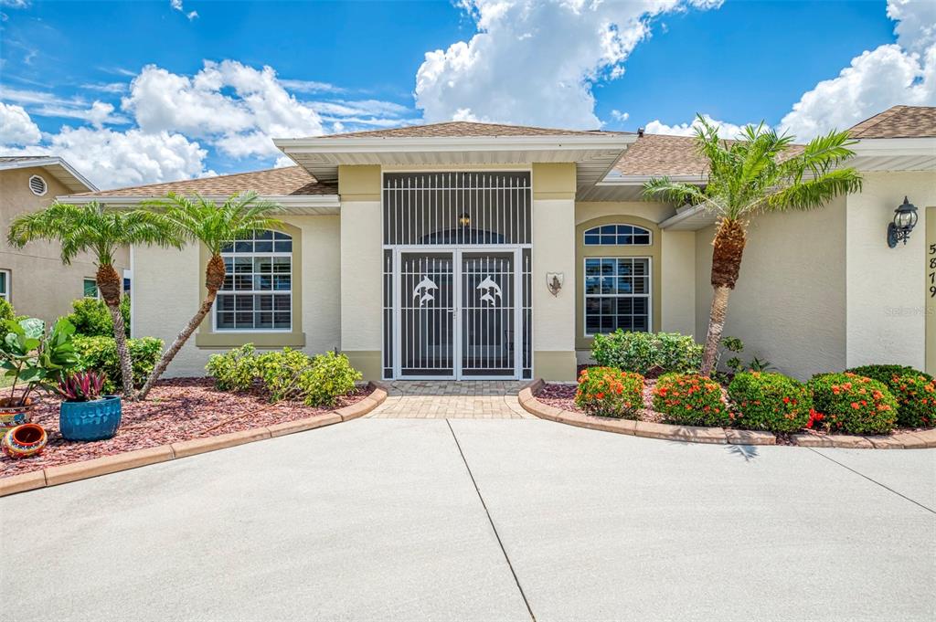 A single-story house exterior features a gated entryway, palm trees, and a paved driveway — 5879 MADISON ROAD, VENICE, FL