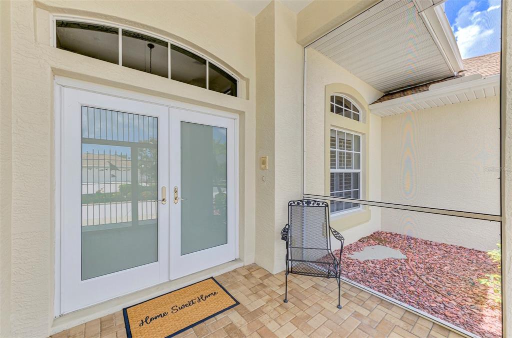 A covered entryway features a double glass door, a metal chair, and a stone floor — 5879 MADISON ROAD, VENICE, FL
