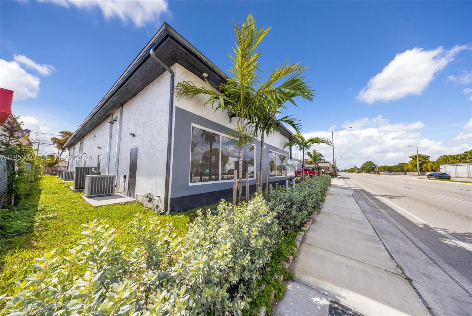 A single-story commercial building with a white stucco facade and gray trim sits beside a road — 4030 Pembroke Rd, Hollywood FL 33021, HOLLYWOOD, FL