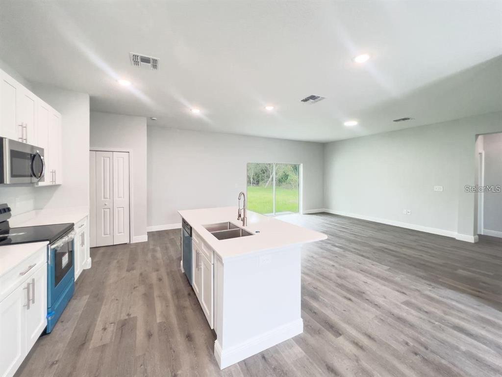 A modern kitchen with white cabinets and a central island opens into a spacious living area — 35 PECAN RUN COURSE, OCALA, FL