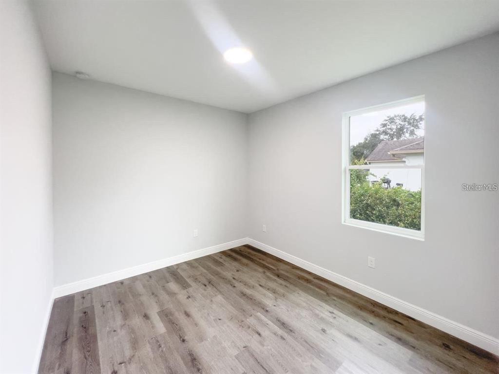 An empty room with light gray walls, wood-look flooring, and a single window — 35 PECAN RUN COURSE, OCALA, FL