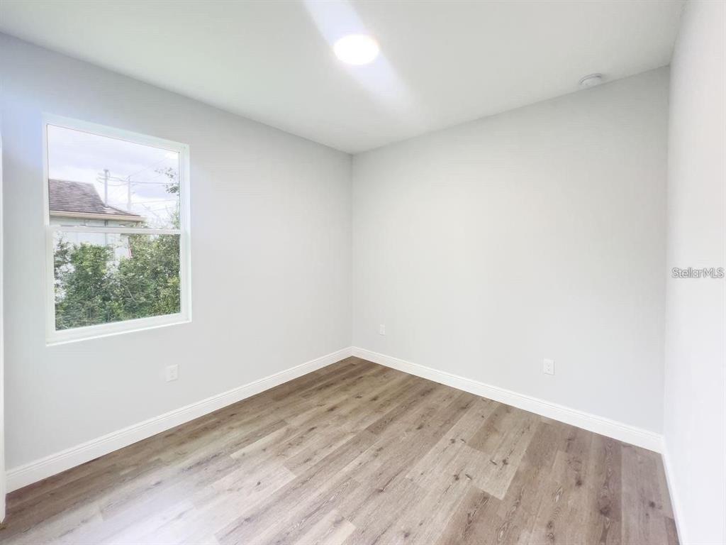 An empty room features light gray walls, white trim, and wood-look flooring — 35 PECAN RUN COURSE, OCALA, FL