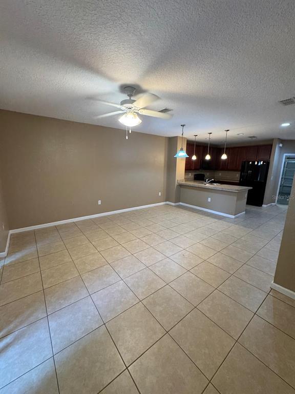 An open-concept living area features beige tile flooring, a ceiling fan, and a kitchen island — 1428 CHELSEA DRIVE, DAVENPORT, FL