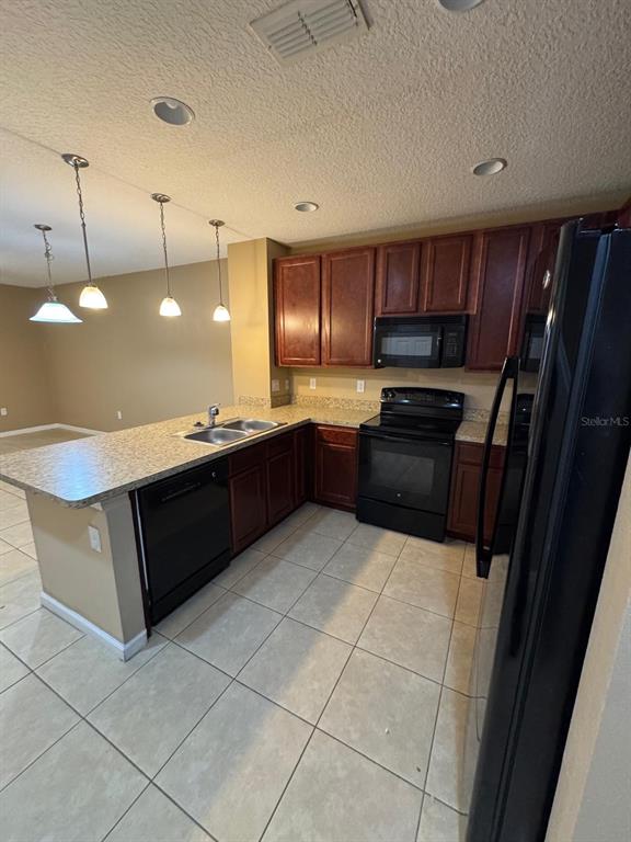 A kitchen with dark wood cabinets, black appliances, and a breakfast bar with pendant lighting — 1428 CHELSEA DRIVE, DAVENPORT, FL