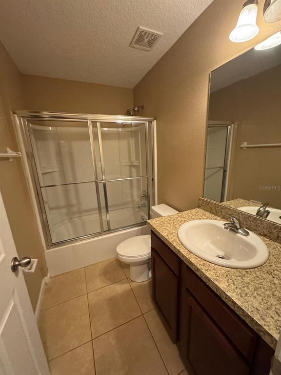 A bathroom features a granite-topped vanity, a toilet, and a shower-tub combination with sliding doors — 1428 CHELSEA DRIVE, DAVENPORT, FL