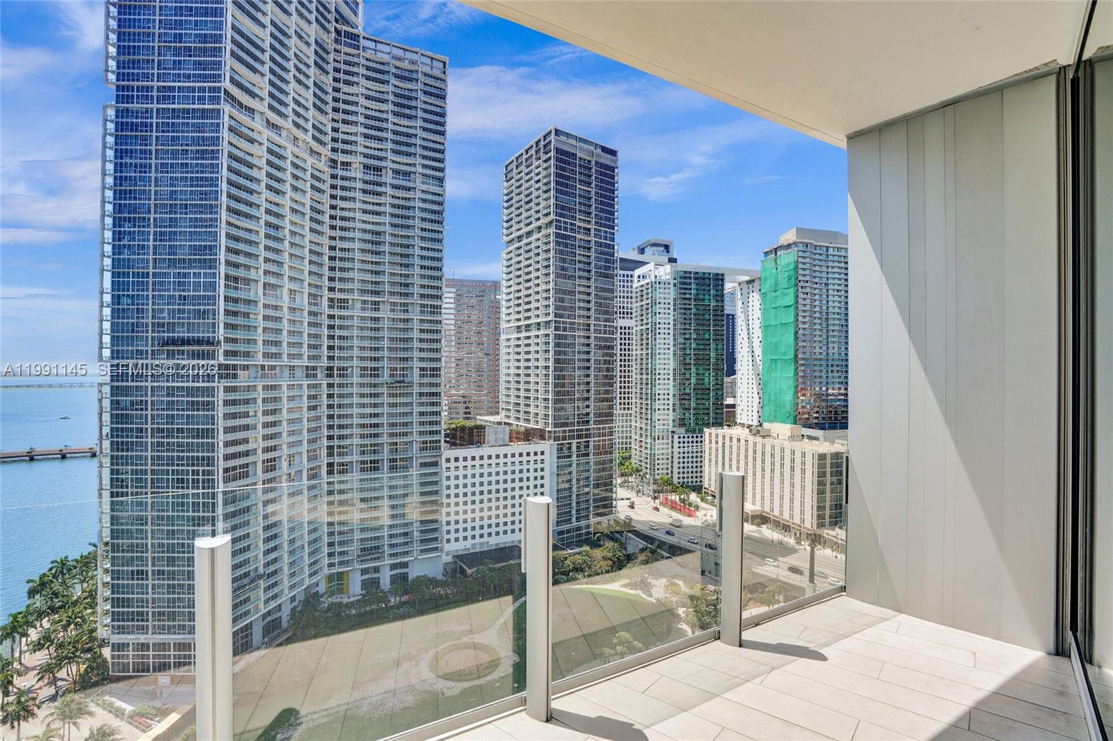 A balcony with a glass railing overlooks a city skyline and a waterfront park — 300 Biscayne Boulevard Way # 2106W, Miami FL 33131, MIAMI, FL
