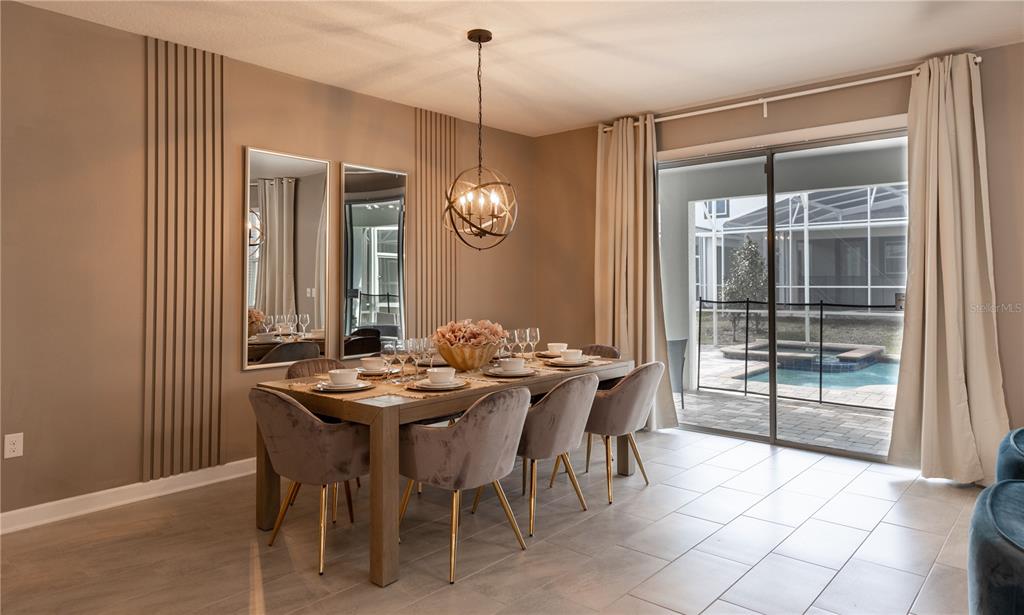 A dining room features a wooden table with six velvet chairs, wall paneling, and sliding doors — 840 DROP SHOT DRIVE, DAVENPORT, FL
