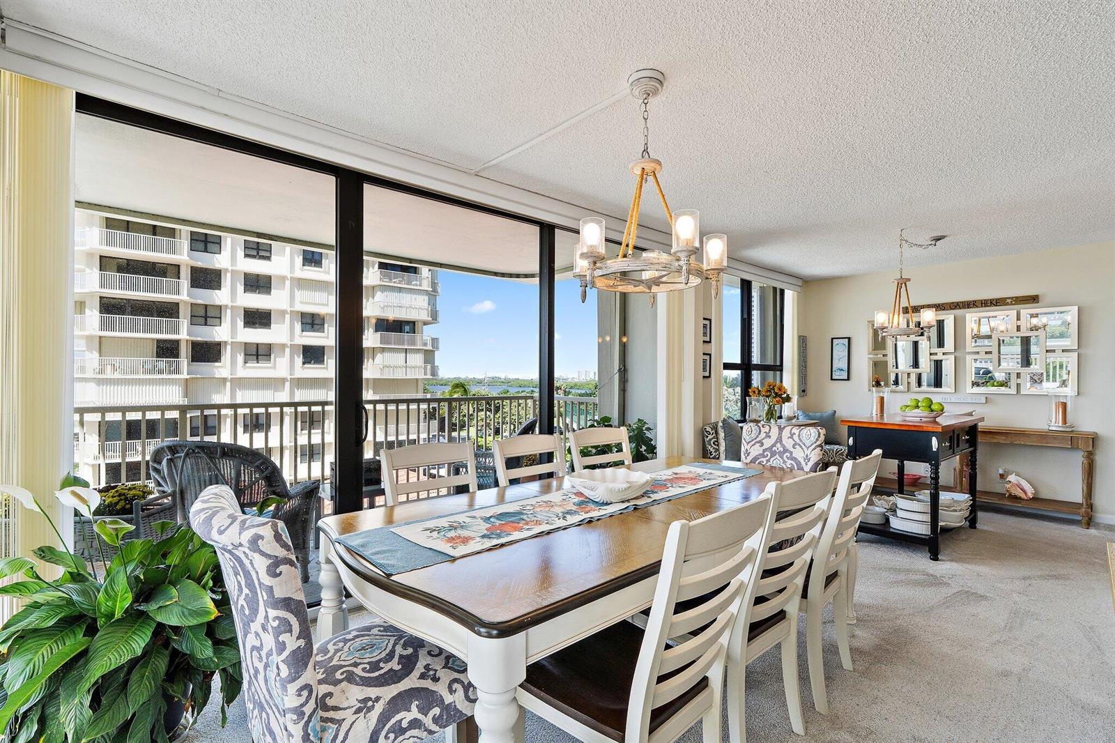 A dining room with a wooden table, white chairs, and a large window overlooking buildings — 5480 N Ocean Drive, Singer Island FL 33404, SINGER ISLAND, FL