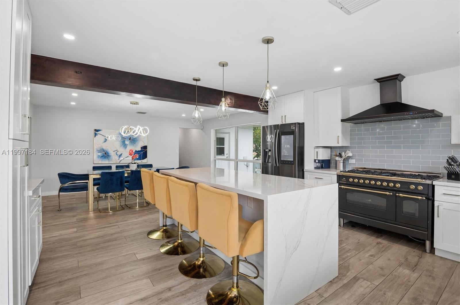 A modern kitchen features a marble waterfall island, gold bar stools, and a dark range — 717 NW 30th St, Wilton Manors FL 33311, WILTON MANORS, FL