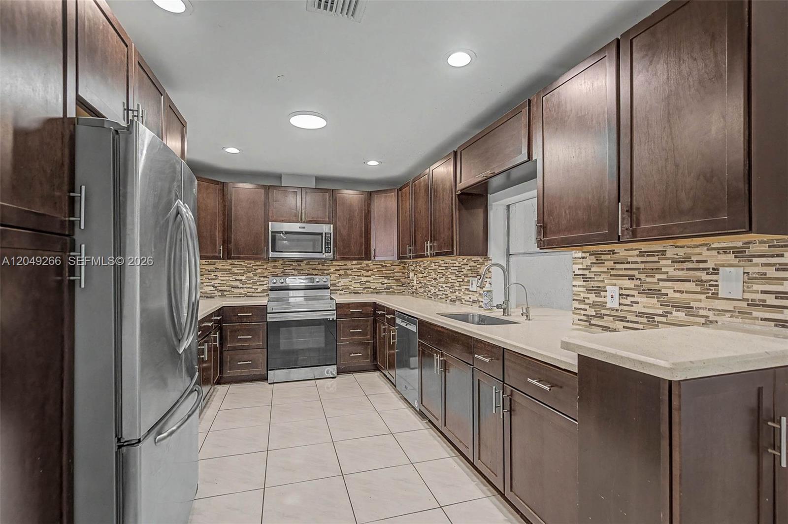 A kitchen features dark wood cabinets, stainless steel appliances, and a tiled backsplash — 11860 SW 81st Rd # 11860, Pinecrest FL 33156, PINECREST, FL