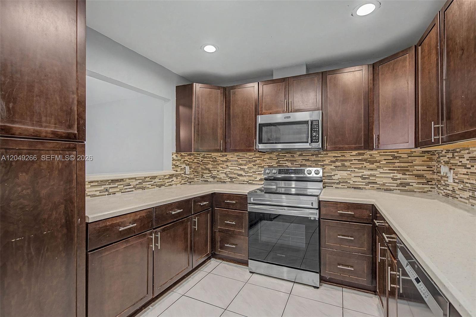 A kitchen features dark wood cabinets, stainless steel appliances, and a mosaic tile backsplash — 11860 SW 81st Rd # 11860, Pinecrest FL 33156, PINECREST, FL
