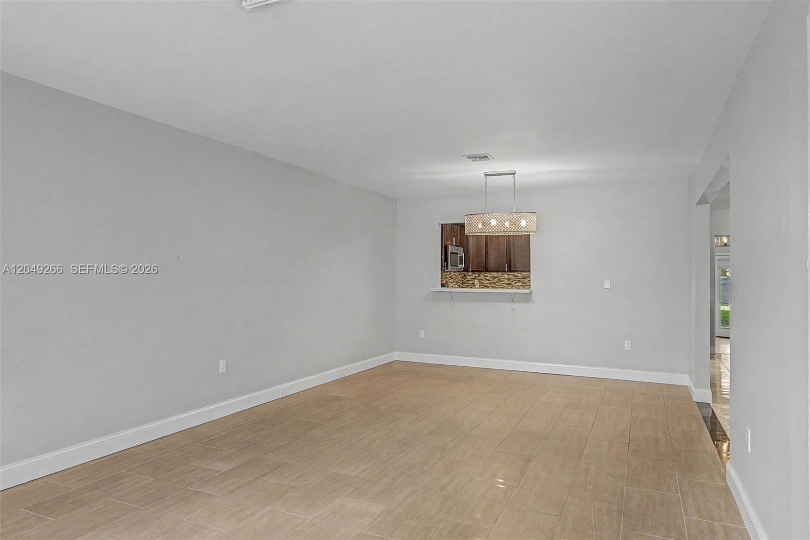 A living room with light gray walls, tile flooring, and a pass-through to the kitchen — 11860 SW 81st Rd # 11860, Pinecrest FL 33156, PINECREST, FL