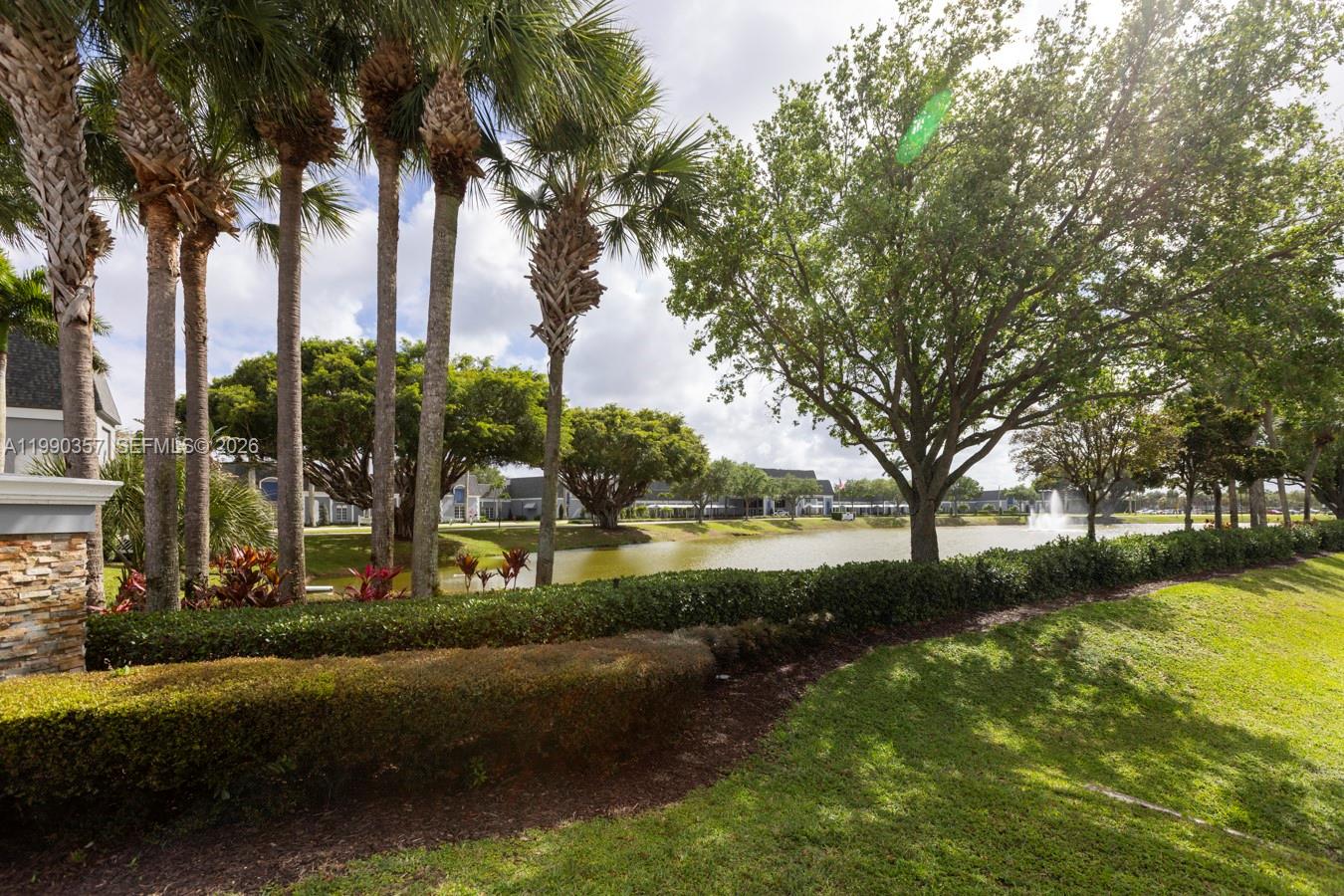 A view of a pond with a fountain surrounded by palm trees and landscaping — 294 Brittany G # 294, Delray Beach FL 33446, DELRAY BEACH, FL