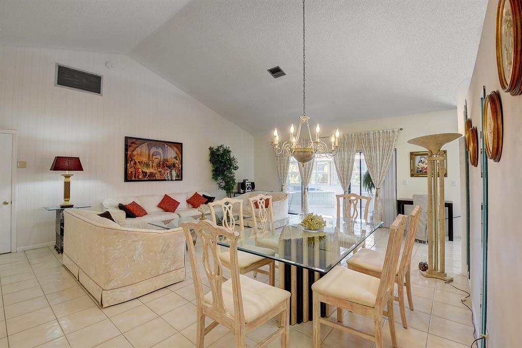 A dining and living area with a glass table, white sofa, and vaulted ceilings — 9565 El Clair Ranch Road, Boynton Beach FL 33437, BOYNTON BEACH, FL