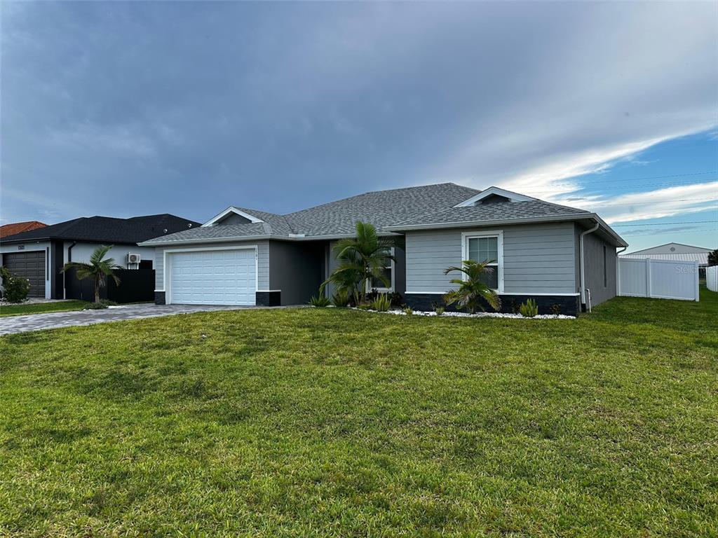 A single-story house with gray siding, a white garage door, and a grassy front yard — 1501 NW 4TH STREET, CAPE CORAL, FL