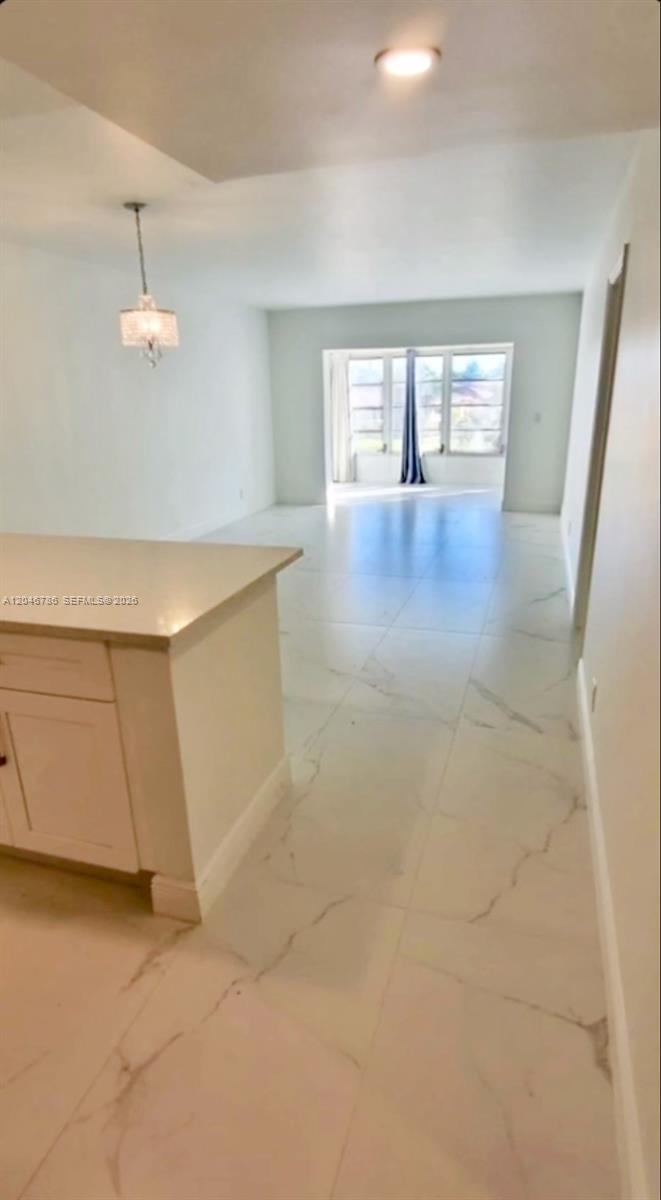 A kitchen island overlooks a bright, open-concept living area with white marble-style tile flooring — 14790 Bonaire Blvd # 202, Delray Beach FL 33446, DELRAY BEACH, FL