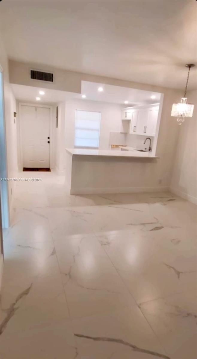A bright dining area features white marble-look tile flooring and an open kitchen with white cabinetry — 14790 Bonaire Blvd # 202, Delray Beach FL 33446, DELRAY BEACH, FL
