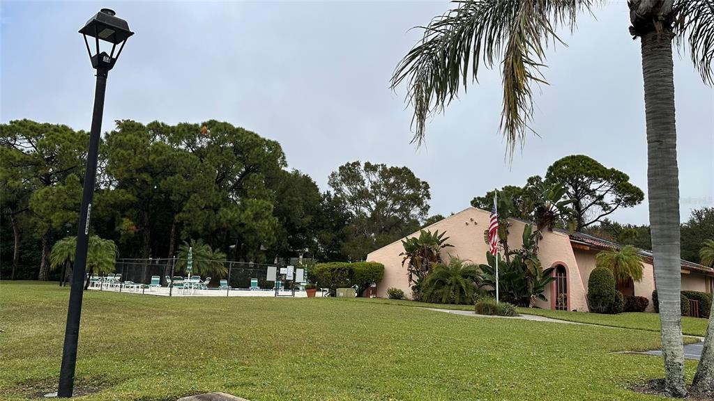A grassy lawn leads to a single-story building with a pool area and palm trees — 9783 86TH AVENUE, SEMINOLE, FL
