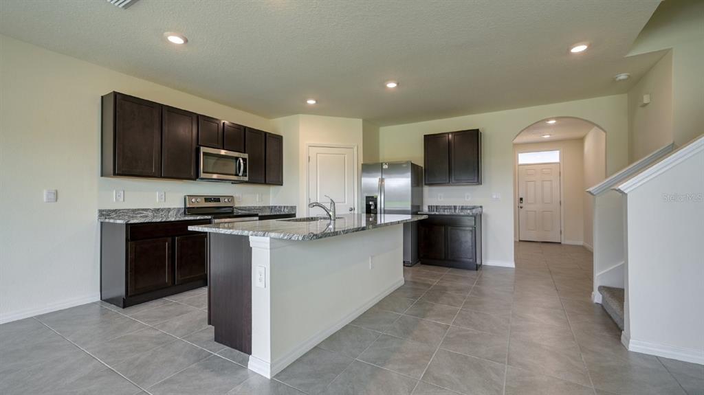 A kitchen with dark cabinets, granite countertops, a center island, and stainless steel appliances — 5657 SOFT SKIES DRIVE, SARASOTA, FL
