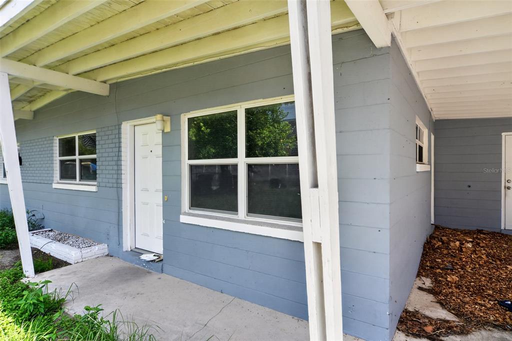 A gray-painted exterior wall features a white front door and two windows under a porch — 4001 MONARCH DRIVE, ORLANDO, FL