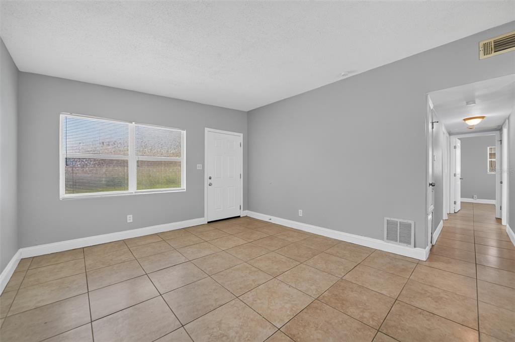 A room with gray walls, tile flooring, a window with blinds, and a white door — 4001 MONARCH DRIVE, ORLANDO, FL