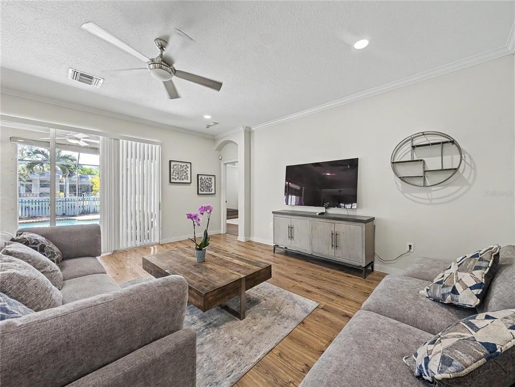 A living room features gray sofas, a wood coffee table, and a wall-mounted television — 4414 67TH AVENUE CIRCLE E, SARASOTA, FL