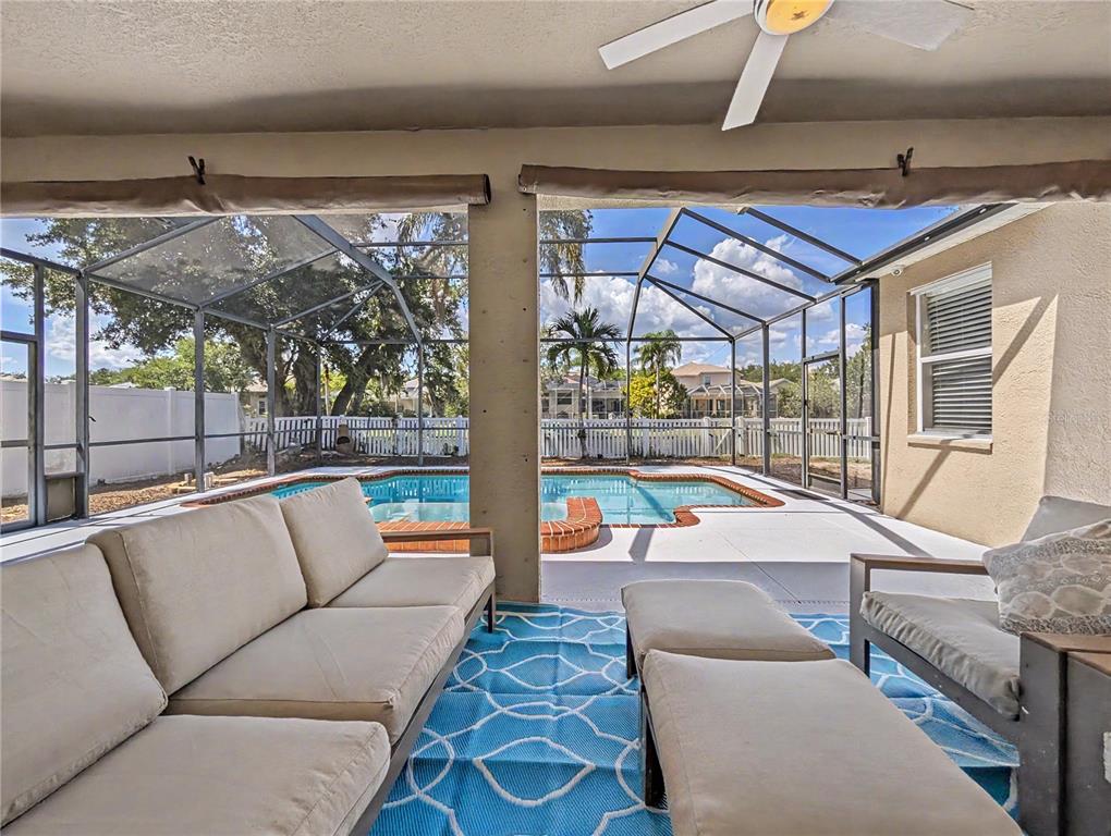 A covered patio features outdoor furniture, a blue patterned rug, and a screened-in swimming pool — 4414 67TH AVENUE CIRCLE E, SARASOTA, FL