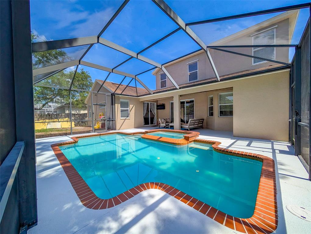 A swimming pool with an attached spa sits inside a screened-in patio area — 4414 67TH AVENUE CIRCLE E, SARASOTA, FL