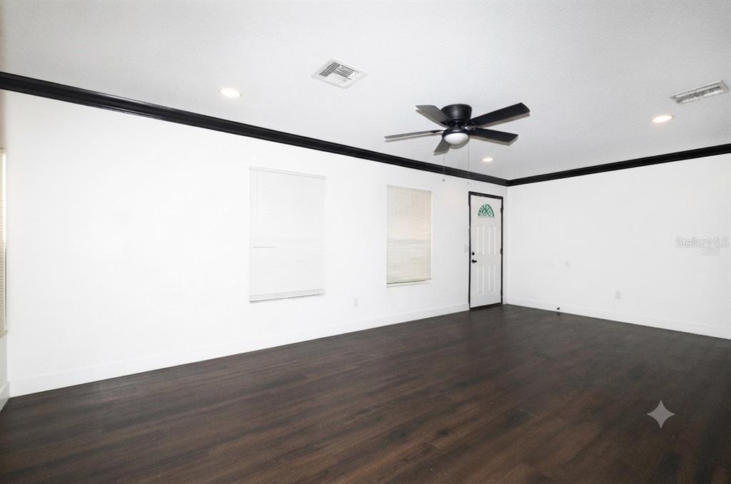 A room with dark wood-look flooring, white walls, black crown molding, and a ceiling fan — 3981 HICKORY TREE ROAD, ST CLOUD, FL