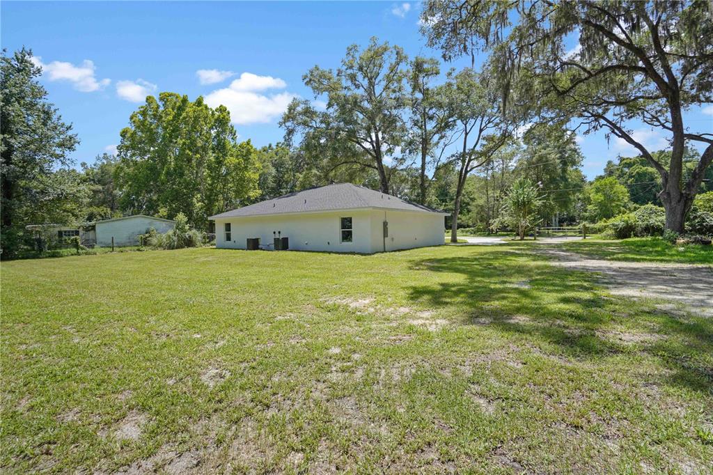 A white, single-story house sits on a large, grassy lot with mature trees — 607 SE 4TH DRIVE UNIT A & B, WILLISTON, FL