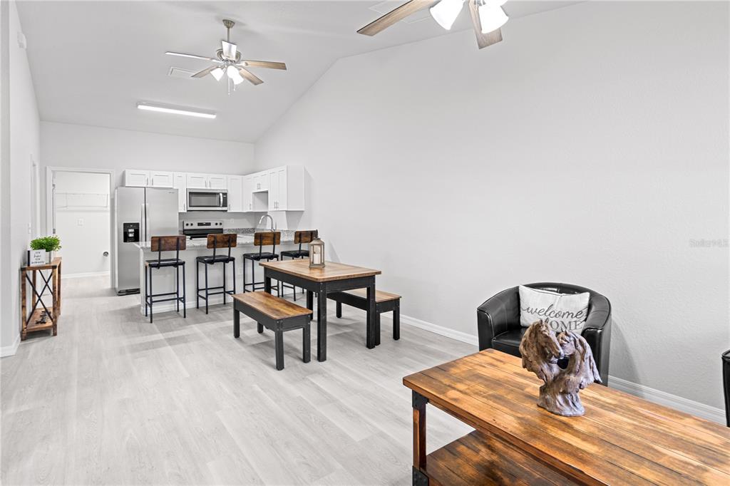 An open-concept kitchen and dining area features white cabinets, light flooring, and rustic wood furniture — 607 SE 4TH DRIVE UNIT A & B, WILLISTON, FL