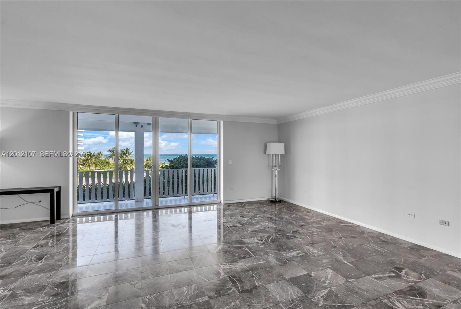 An empty room features gray marble flooring, white walls, and sliding glass doors overlooking the ocean — 200 Ocean Lane Dr # 407, Key Biscayne FL 33149, KEY BISCAYNE, FL