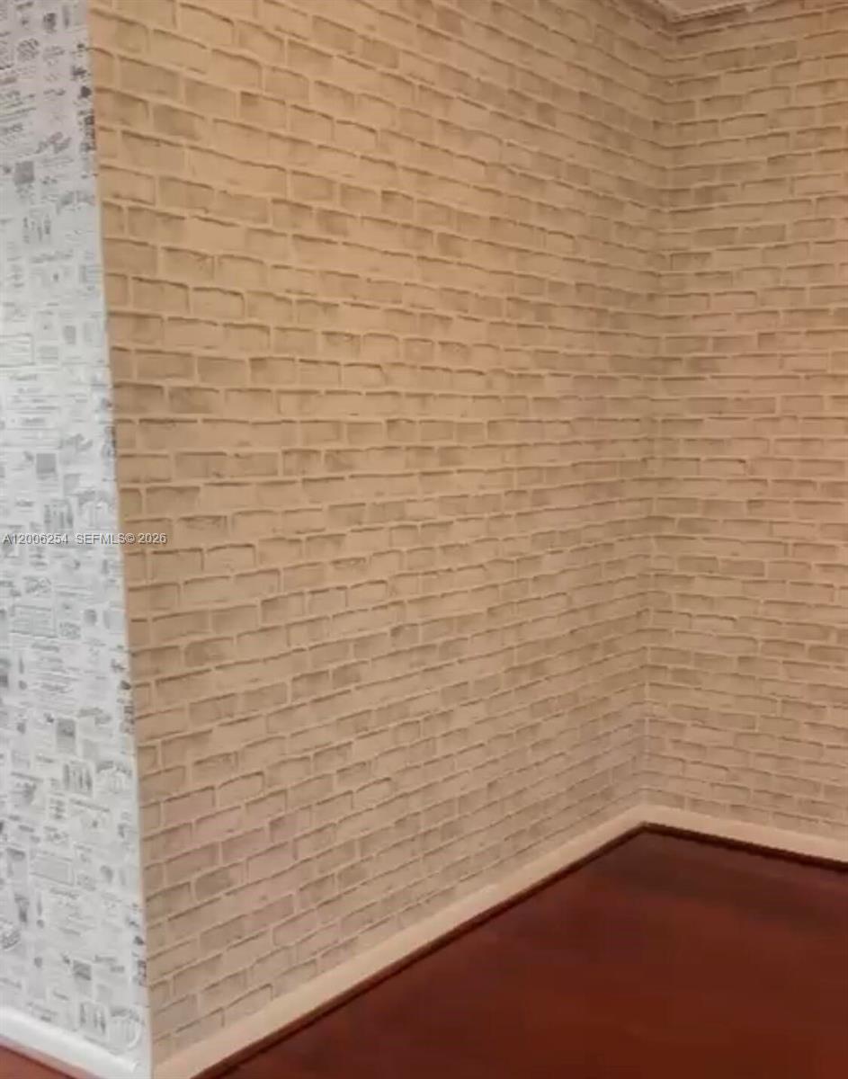 A room corner features light-colored faux brick wallpaper and dark wood flooring — 1000 West Ave # 1105, Miami Beach FL 33139, MIAMI BEACH, FL