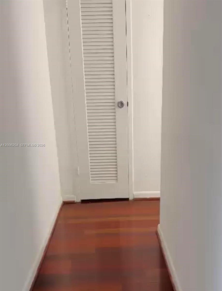 A narrow hallway features white walls, a louvered door, and dark wood flooring — 1000 West Ave # 1105, Miami Beach FL 33139, MIAMI BEACH, FL