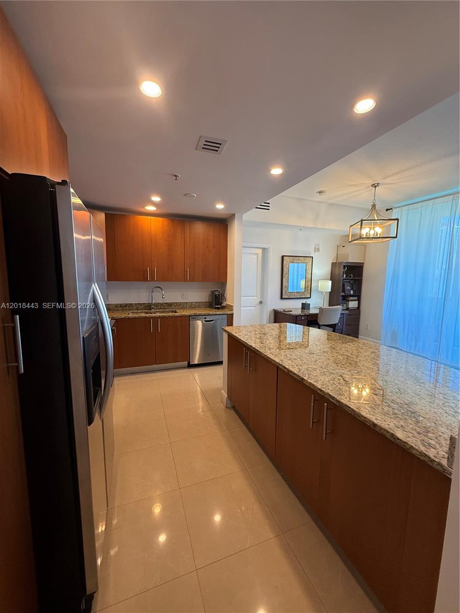 A kitchen features wood cabinets, granite countertops, stainless steel appliances, and tile flooring — 1945 S Ocean Dr # 312, Hallandale Beach FL 33009, HALLANDALE BEACH, FL