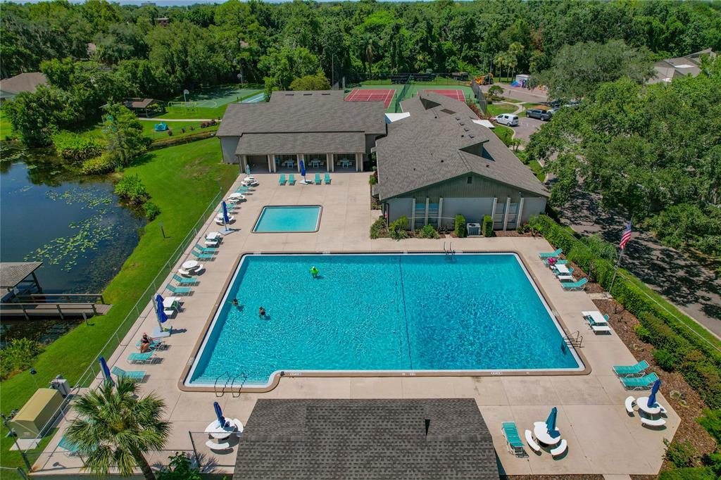 An aerial view shows a large swimming pool, a smaller pool, and a clubhouse building — 805 WESTWIND LANE, FERN PARK, FL