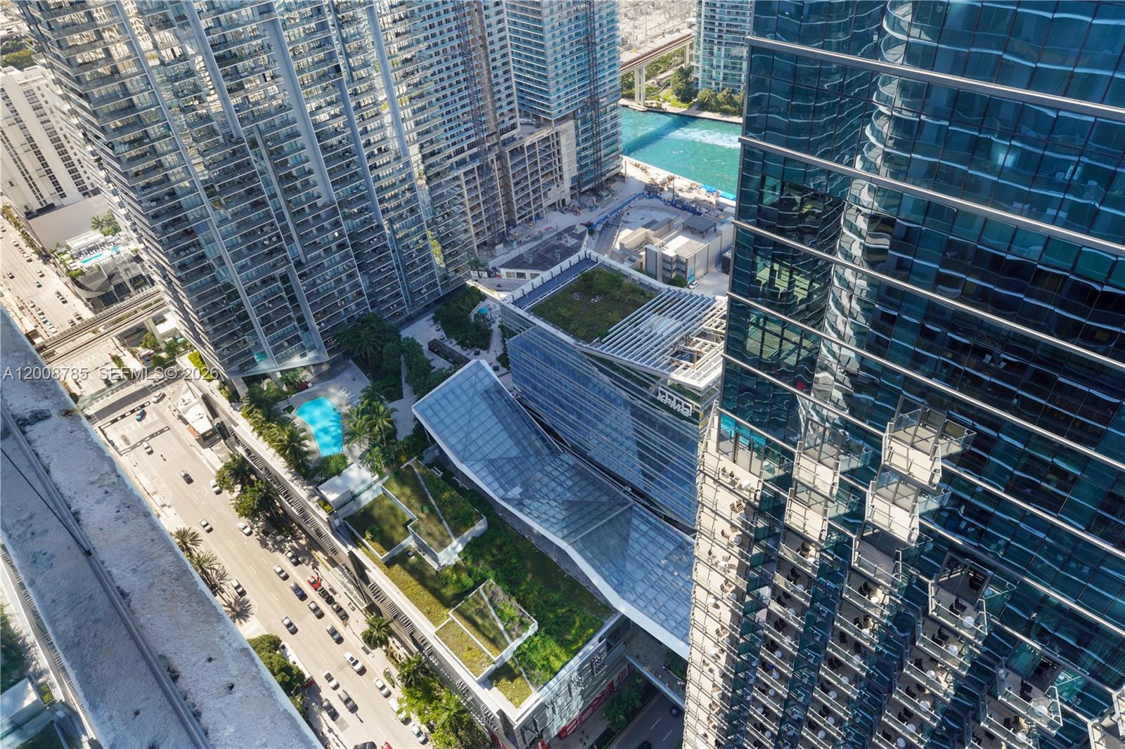 An aerial view shows a modern urban complex with glass skyscrapers, green roofs, and pools — 801 S Miami Ave # 5206, Miami FL 33130, MIAMI, FL