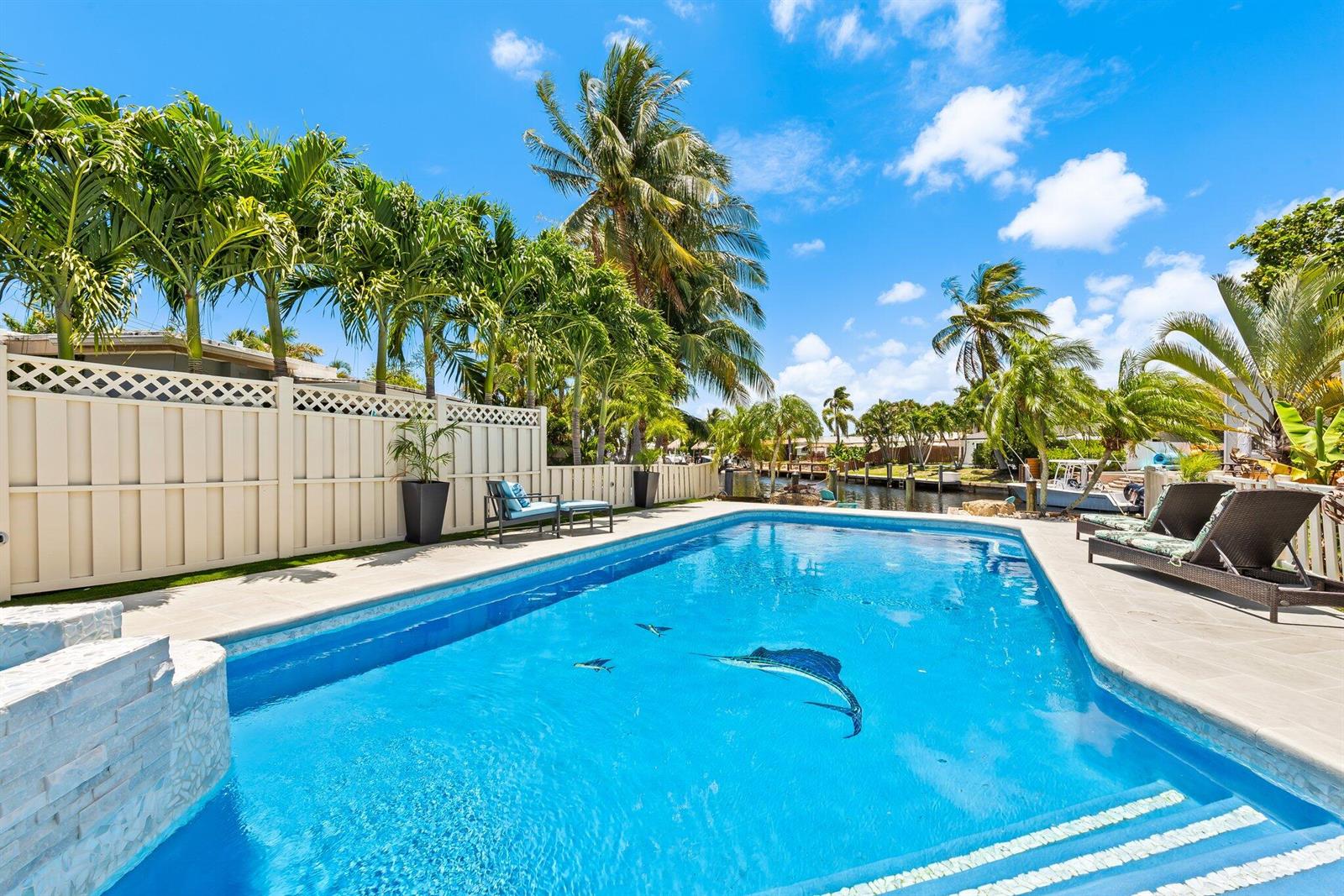 A swimming pool with a sailfish mural sits on a patio next to a canal — 581 SE 5th Avenue, Pompano Beach FL 33060, POMPANO BEACH, FL