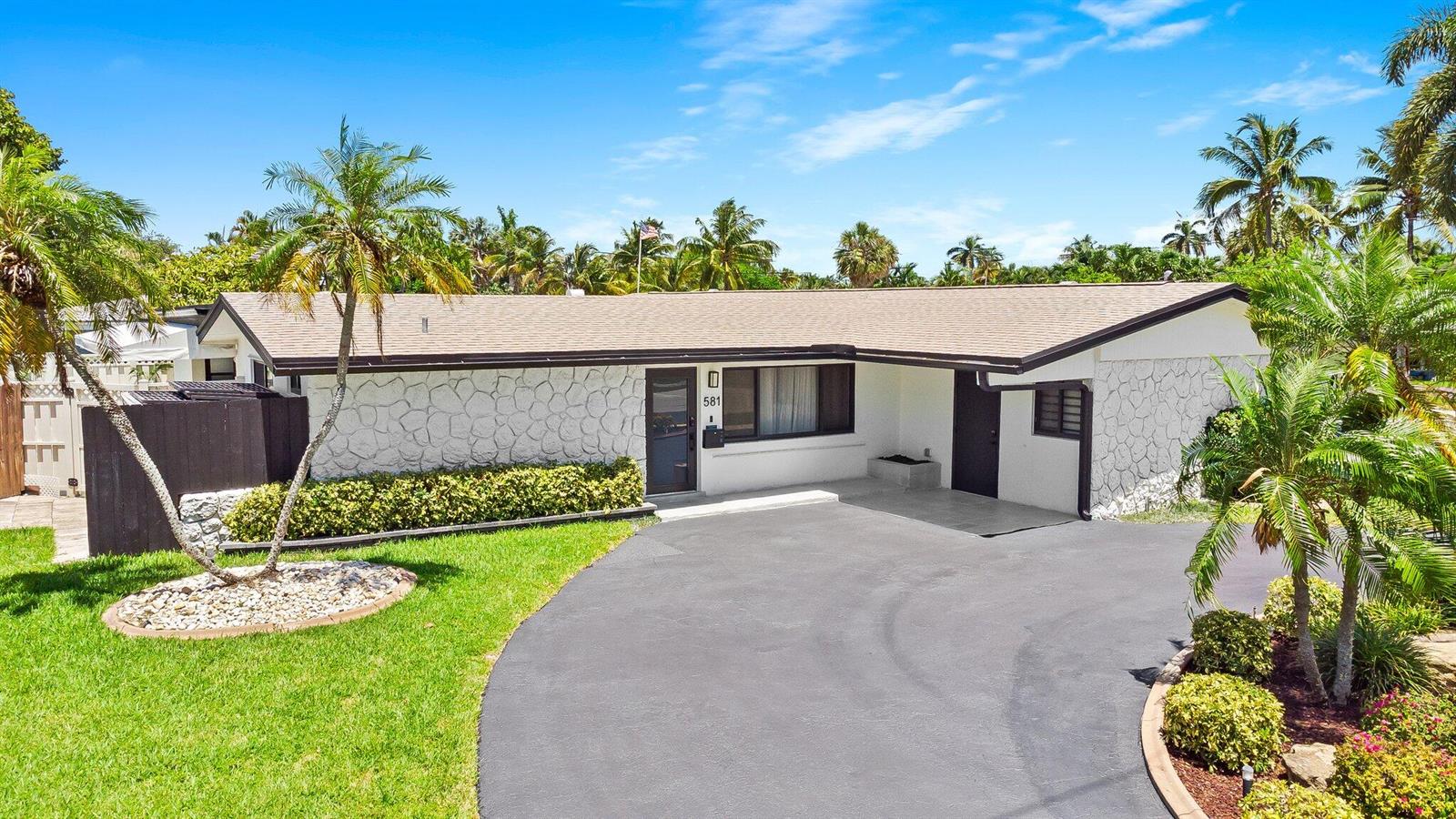 A single-story house with white stone siding, a dark roof, and a paved driveway — 581 SE 5th Avenue, Pompano Beach FL 33060, POMPANO BEACH, FL