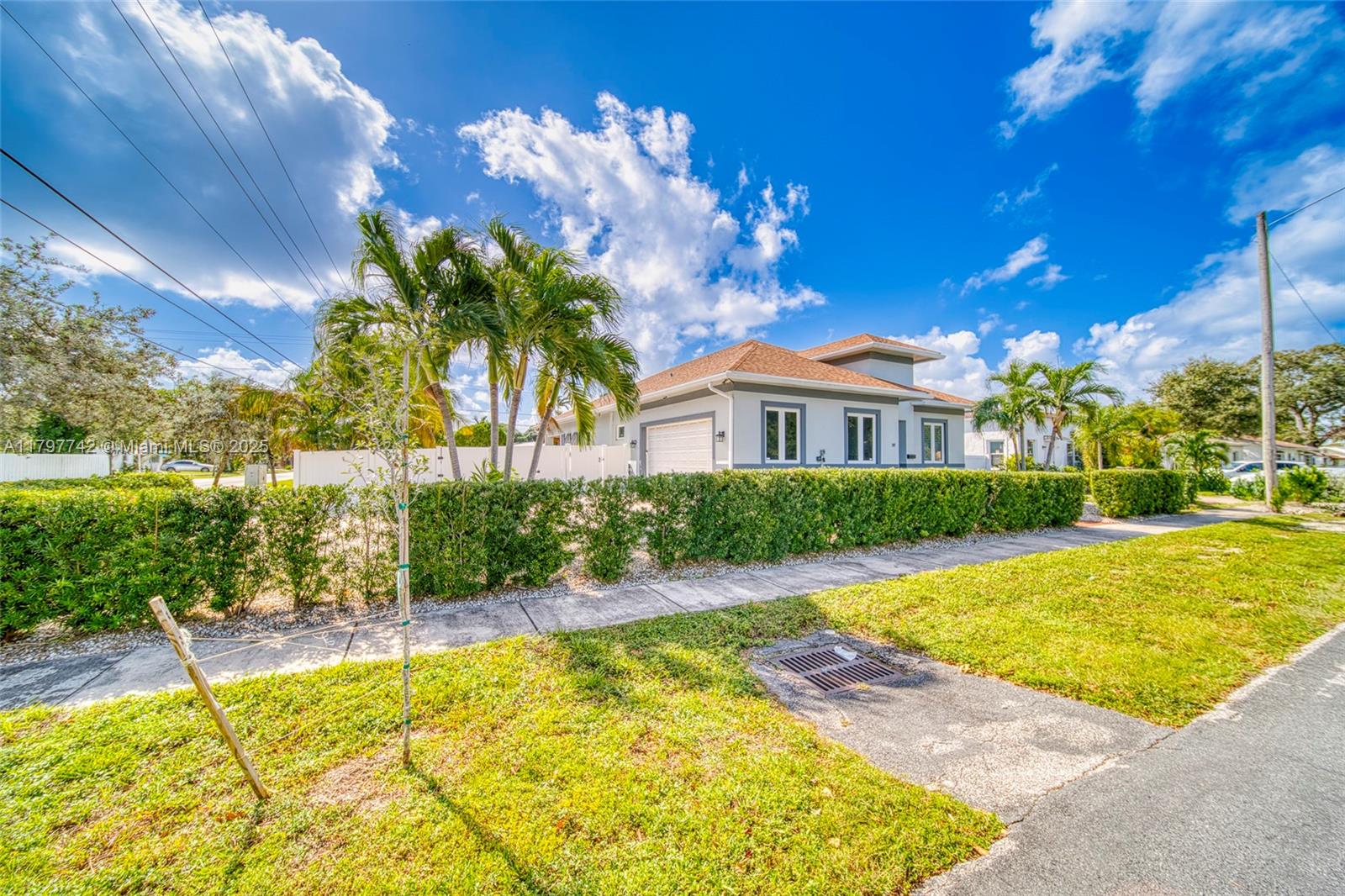 A single-story house with a white exterior, a garage, and a manicured hedge — 207 SW 11th St, Dania Beach FL 33004, DANIA BEACH, FL