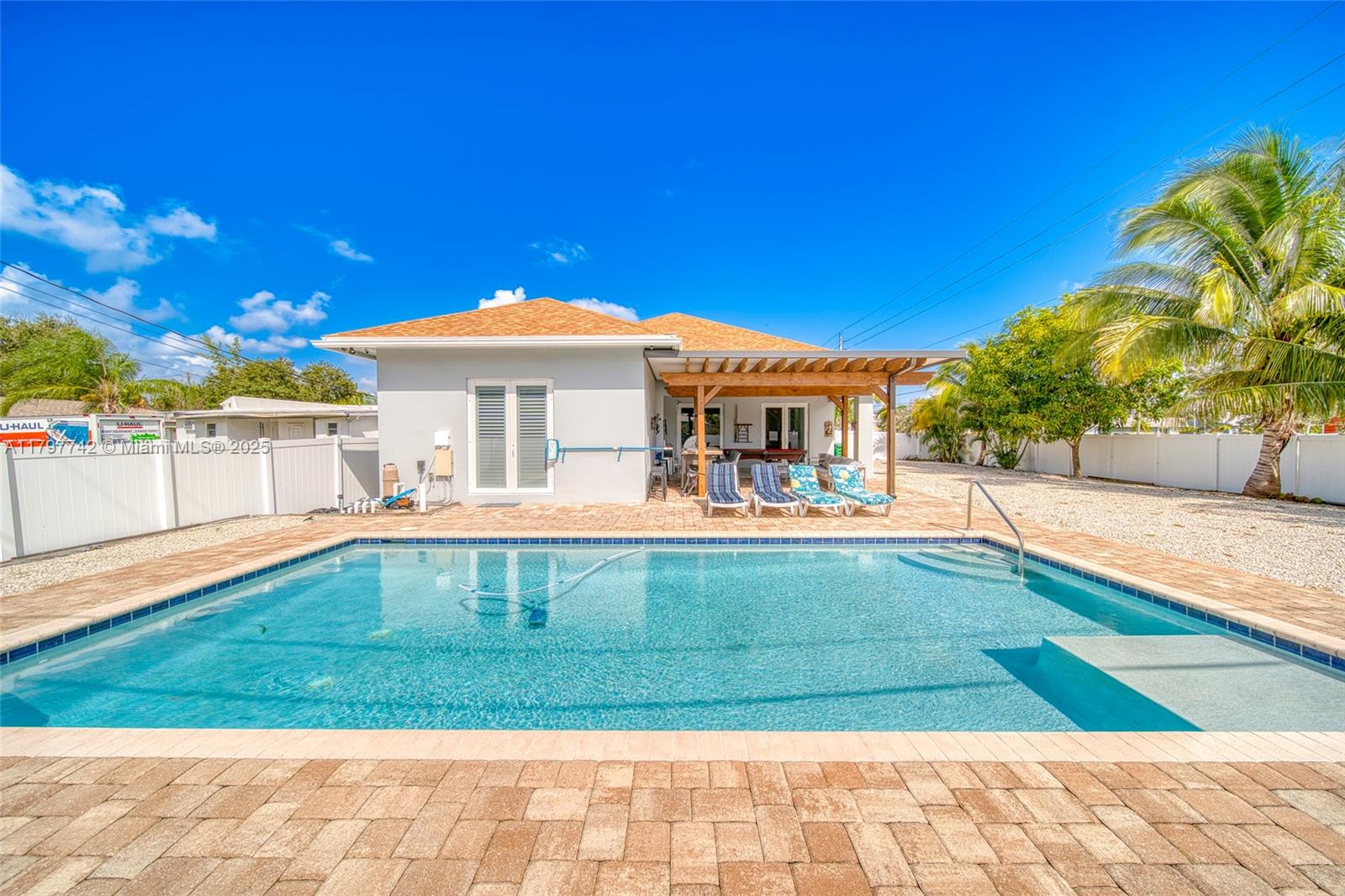 A backyard features a swimming pool, a covered patio with lounge chairs, and a house — 207 SW 11th St, Dania Beach FL 33004, DANIA BEACH, FL