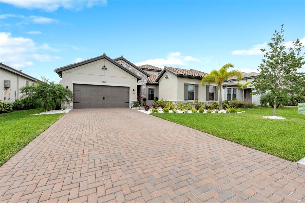 A single-story house with a paved driveway, a two-car garage, and a landscaped front yard — 2028 WOODLEAF HAMMOCK COURT, BRADENTON, FL